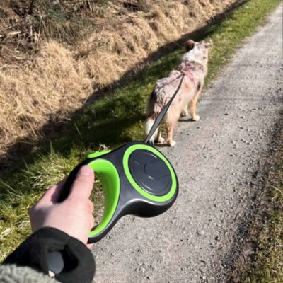laisse de chien enrouleur vert vue main, balade sur chemin, corde fine tendue pour controle doux MaxLeash™