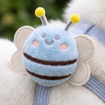 Gros plan sur l'abeille en peluche bleue du harnais petit chien, avec ses rayures marron, ses ailes crème et ses antennes à pompons jaunes