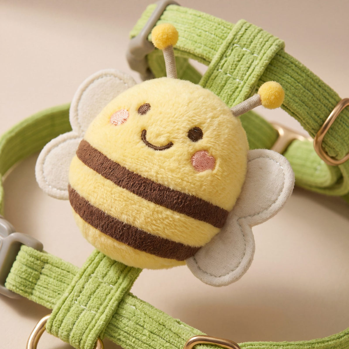 Gros plan sur l'abeille 3D en peluche cousue sur la sangle en velours côtelé vert pomme du harnais