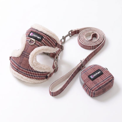 Chien souriant sur l'herbe portant le harnais petit chien tartan bordeaux avec sa laisse et sa pochette