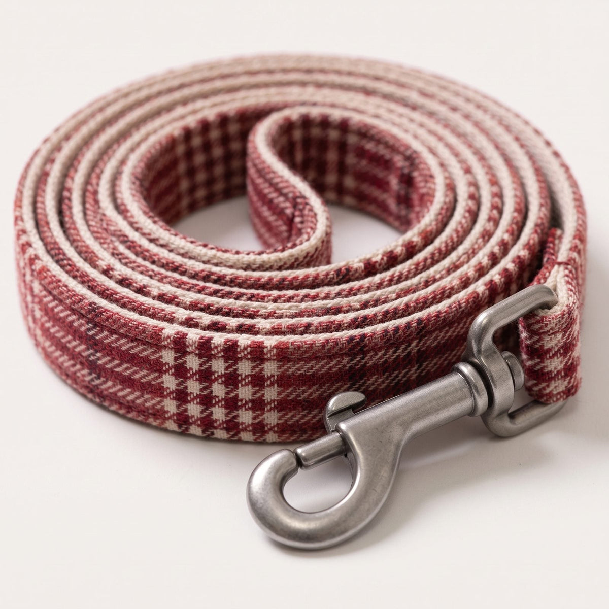Gros plan sur le clip à enclenchement rapide du harnais petit chien tartan bordeaux