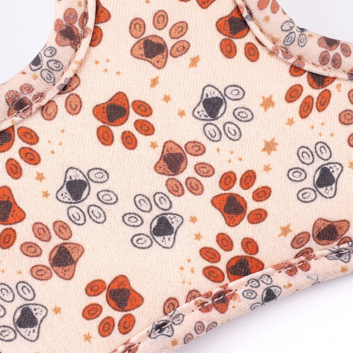 Gros plan sur le tissu imprimé empreintes de pattes du harnais pour petit chien, texture et motif du tissu bien visibles