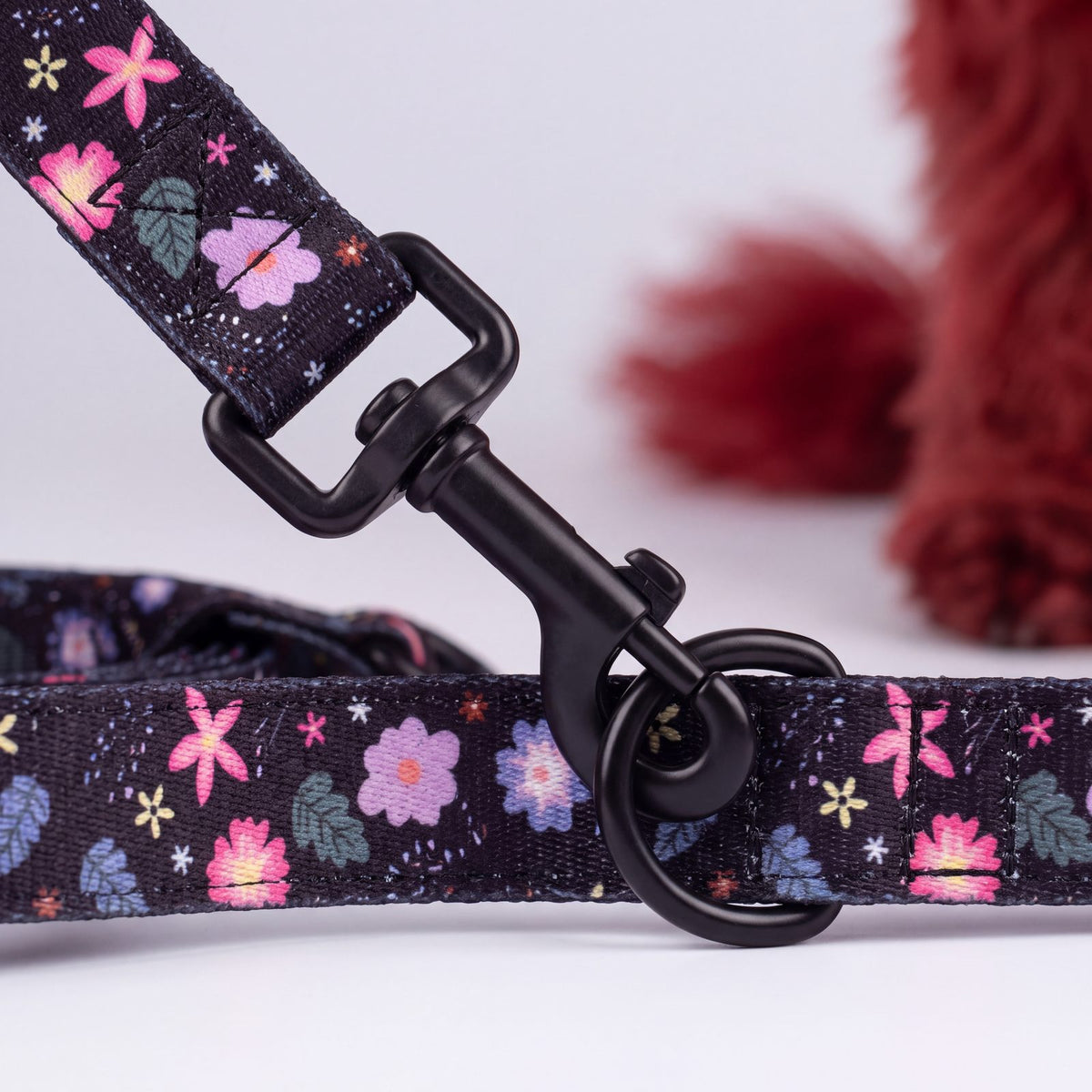 Gros plan sur le mousqueton pivotant et l'anneau du collier à imprimé floral pour petit chien