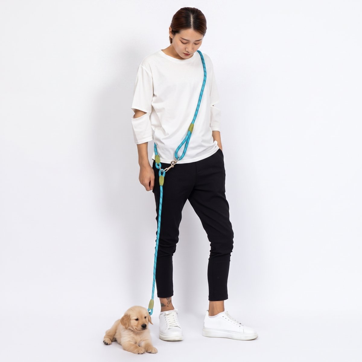 Chiot golden retriever sur fond blanc, laisse chien main libre PawSync en corde turquoise portée en bandoulière