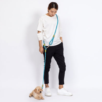 Chiot golden retriever sur fond blanc, laisse chien main libre PawSync en corde turquoise portée en bandoulière