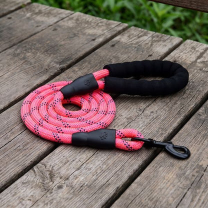 Laisse pour chien corde TrekLine Chien store rose fluo avec poignée en mousse noire confortable et mousqueton d'attache sur une table en bois de jardin