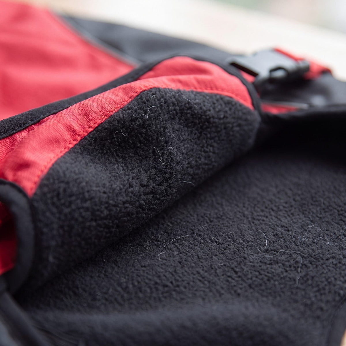 Gros plan sur la doublure polaire noire douce du manteau d'hiver chaud pour chien rouge