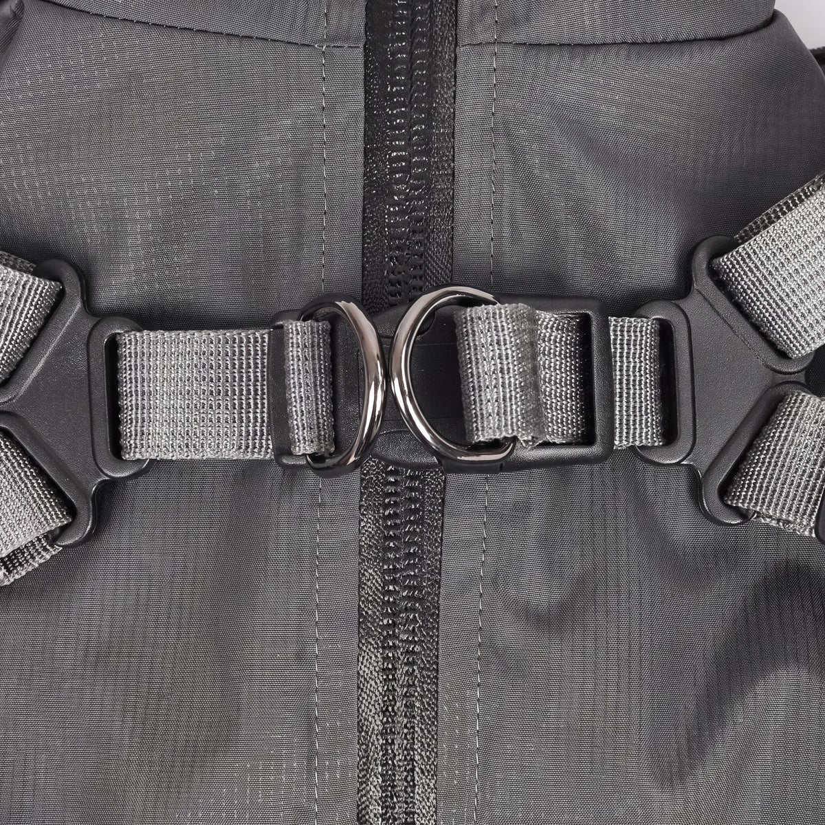 Gros plan sur le harnais intégré du manteau pour chien imperméable : sangles réglables, boucle et deux anneaux métalliques de chaque côté du zip dorsal