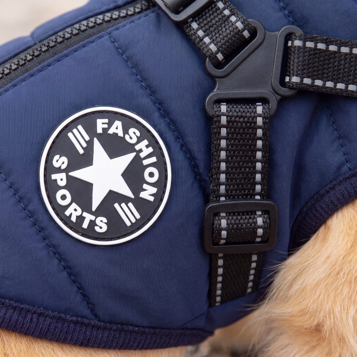 Gros plan sur l'écusson rond Fashion Sports et les sangles réfléchissantes du manteau pour chien bleu marine