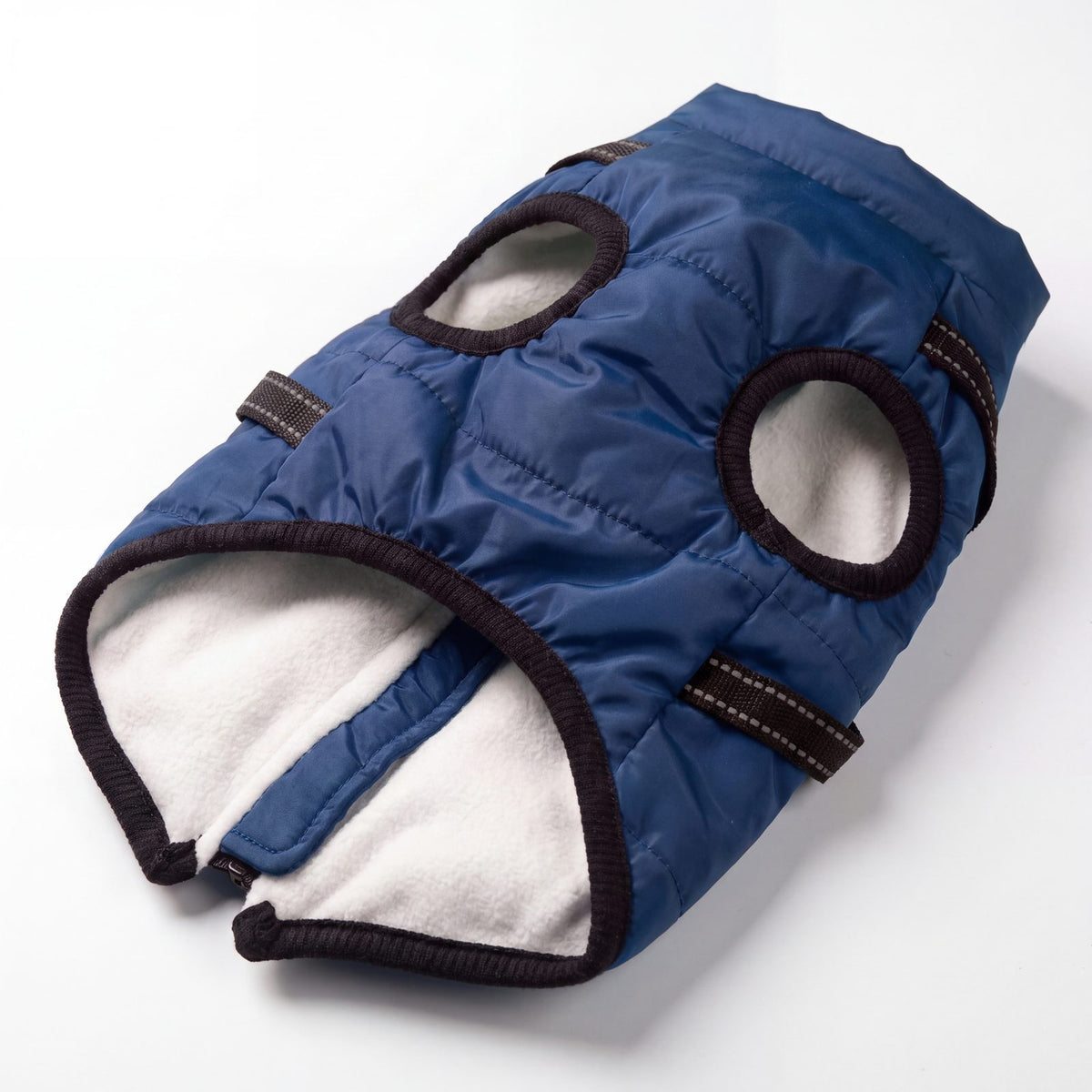 Intérieur polaire blanc et bords côtelés du manteau pour chien bleu marine posé à plat
