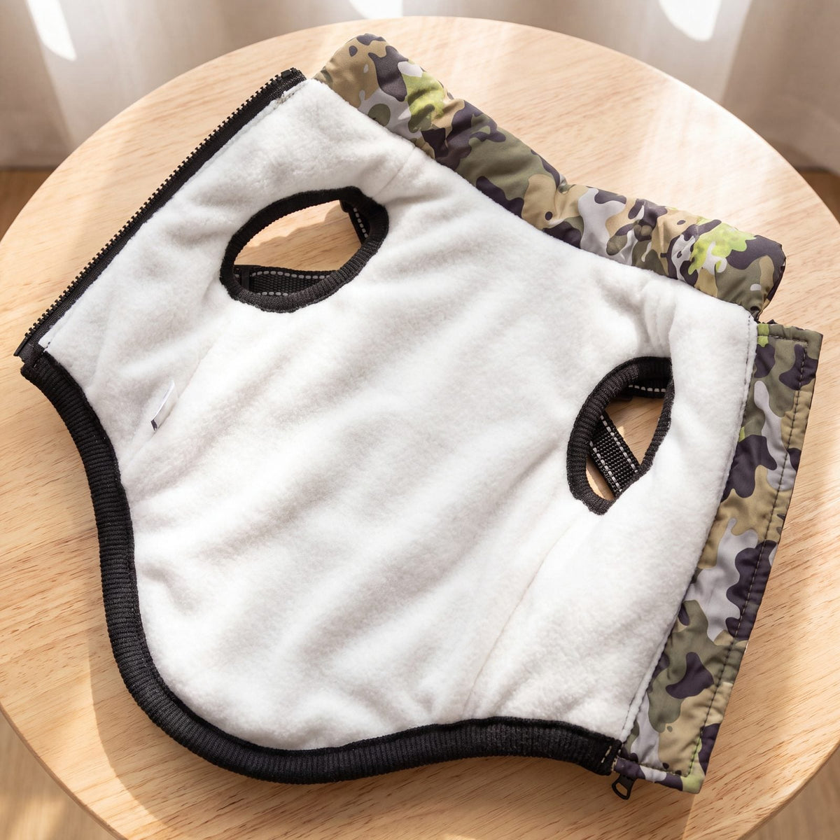 Intérieur doublé de polaire blanche du manteau camouflage pour chien posé sur une table en bois