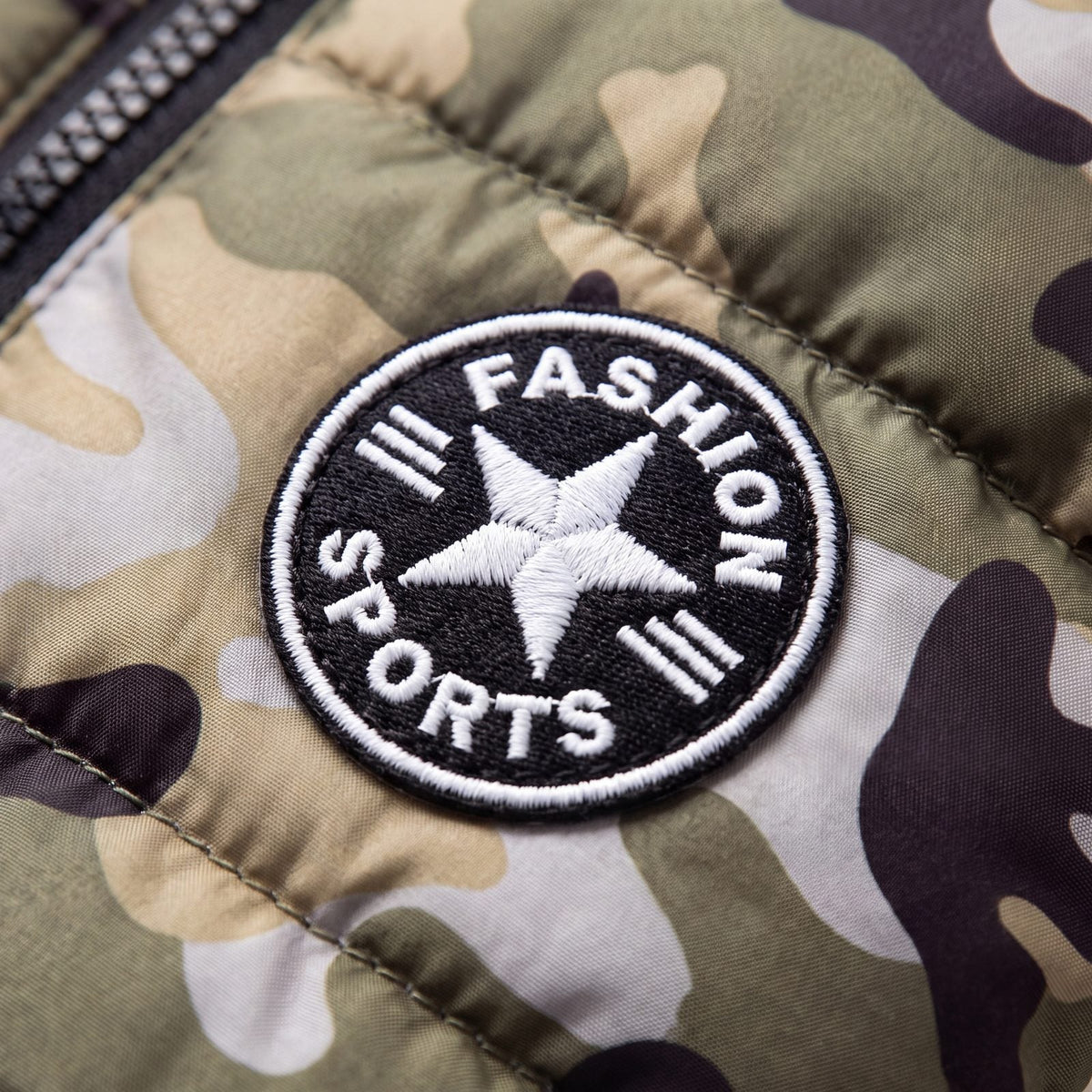 Gros plan sur l'écusson étoile noir et blanc brodé sur le tissu camouflage du manteau pour chien