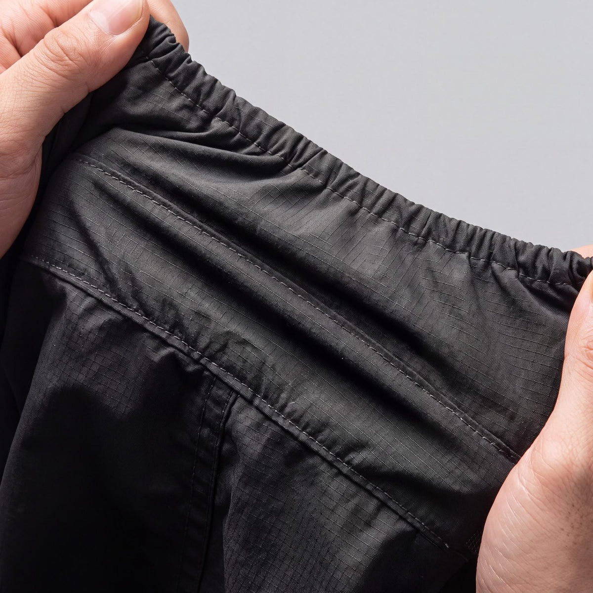 Vue de l'intérieur du manteau pour chien : tissu ripstop, coutures renforcées et manchette élastique, tenus à deux mains