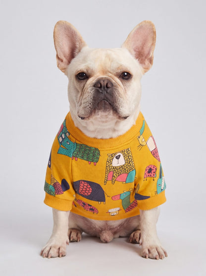 Bouledogue français assis de face portant un pull chien jaune doublé polaire à motif d'animaux colorés