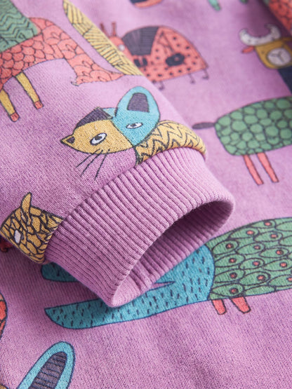 Gros plan sur le poignet côtelé violet du pull chien doublé polaire, avec l'imprimé d'animaux colorés