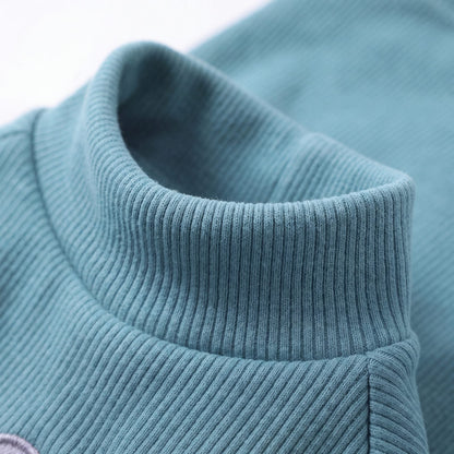 Gros plan sur le col montant du pull chien turquoise en maille lisse