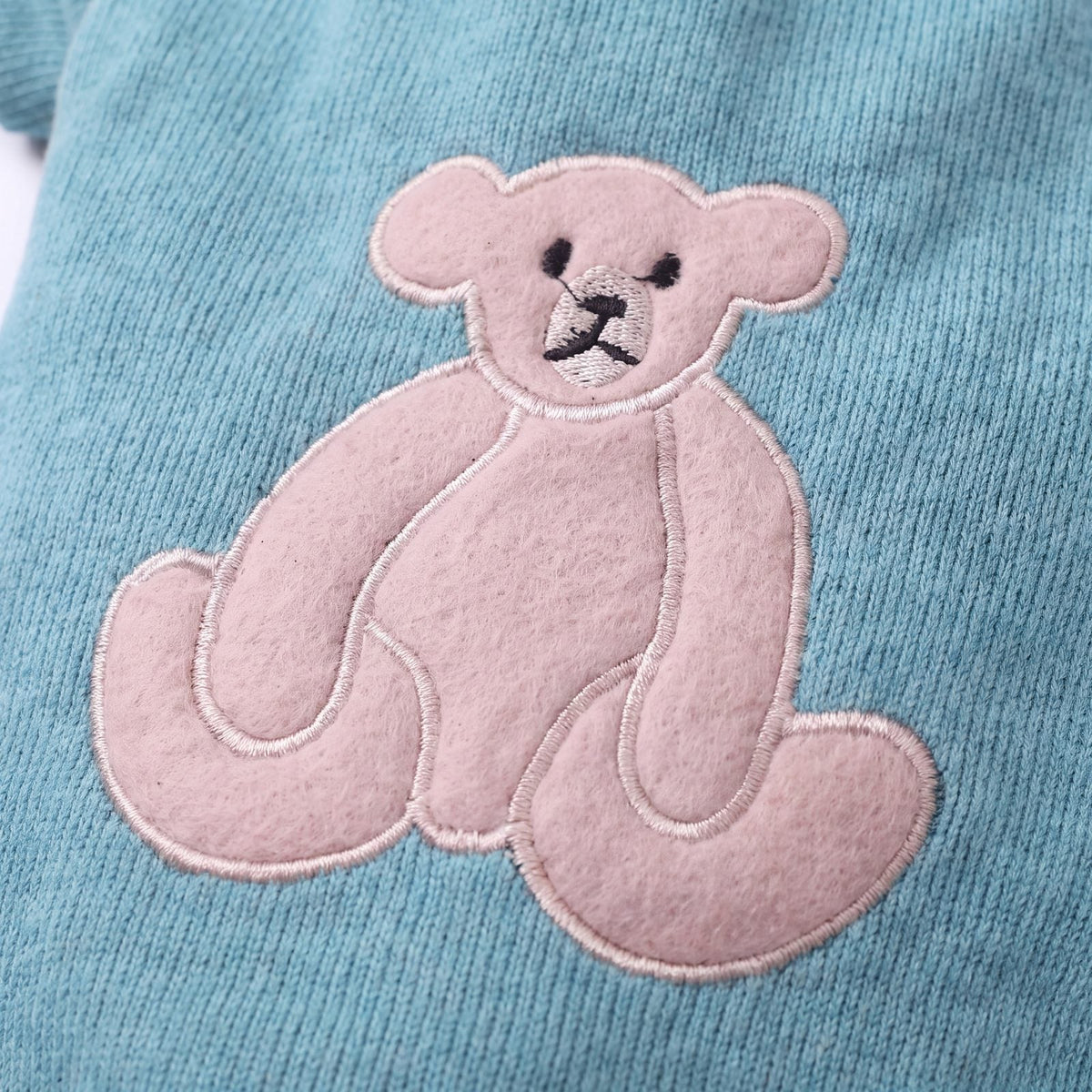 Gros plan sur le grand ourson appliqué dans le dos du pull chien turquoise