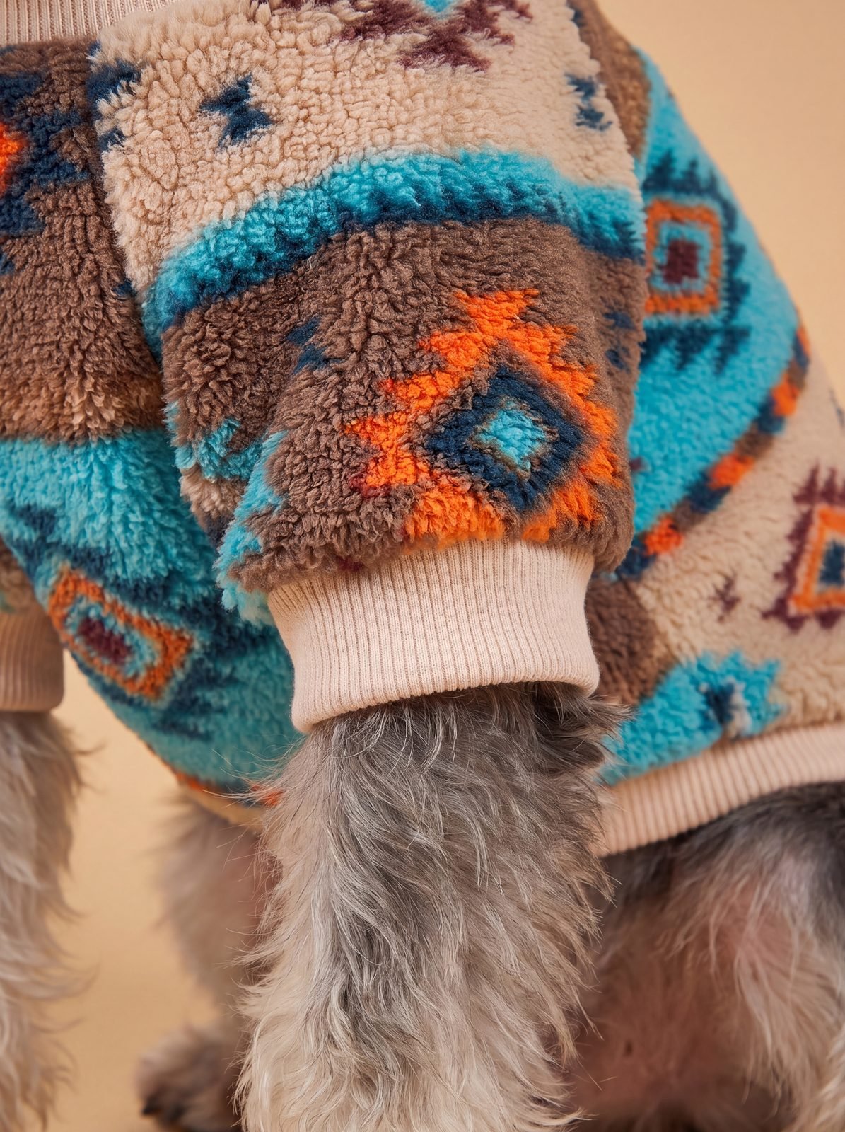 Gros plan sur le bord-côte beige de la manche du pull chien sherpa turquoise
