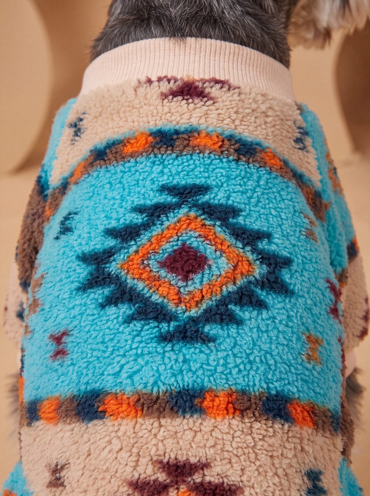 Gros plan sur le motif ethnique du pull chien sherpa turquoise