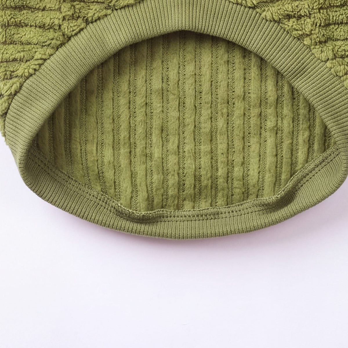 Zoom sur la doublure côtelée douce du pull teddy vert, vue de l'intérieur