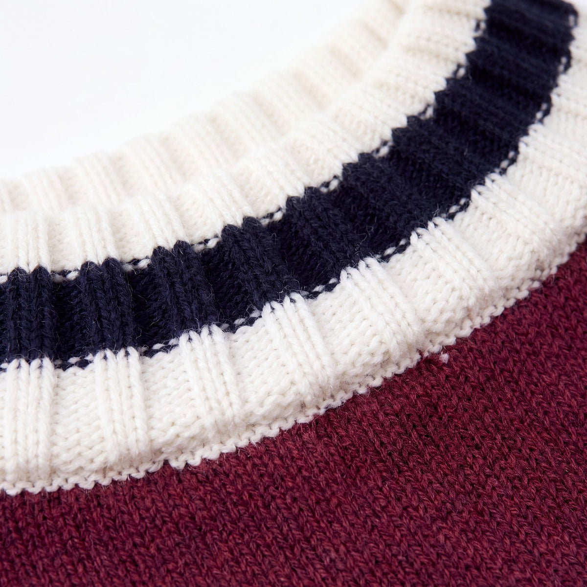 Gros plan sur le col côtelé rayé crème et bleu marine d'un pull chien tricot bordeaux