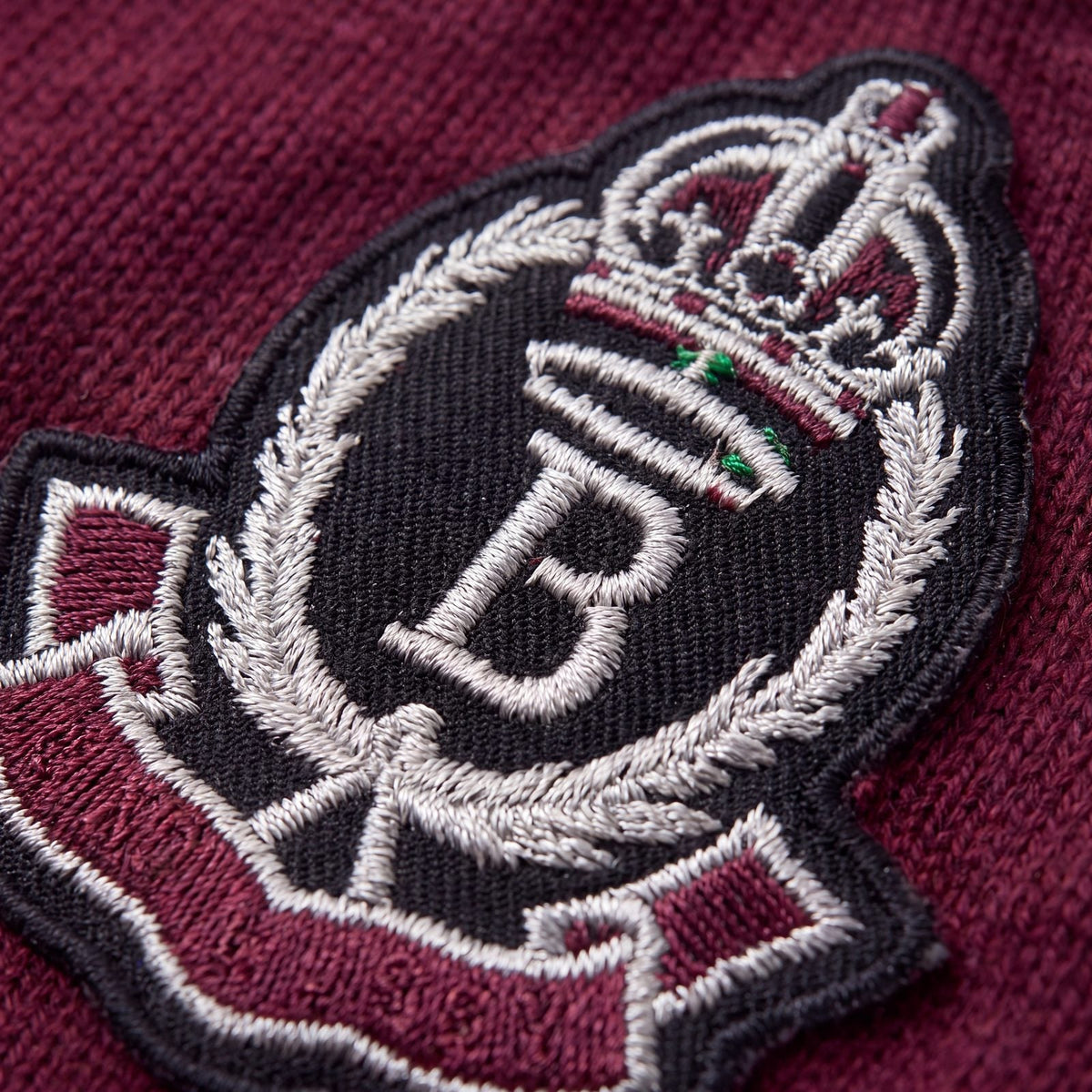 Gros plan sur l'écusson brodé d'un pull chien tricot bordeaux