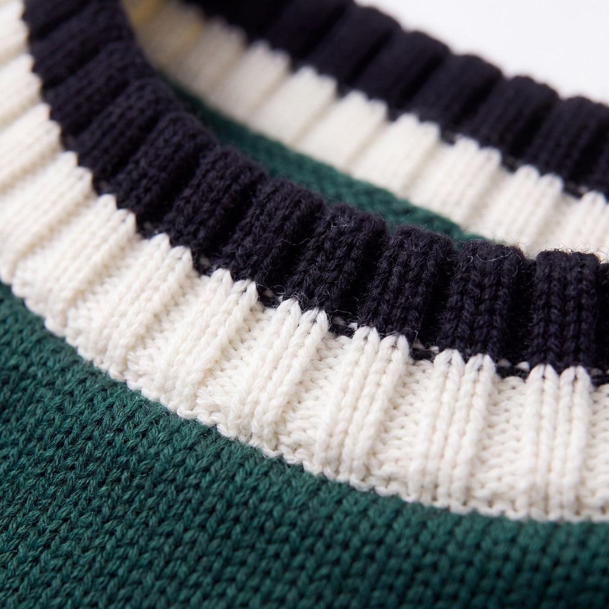 Gros plan sur le col côtelé rayé crème et bleu marine du pull chien tricot vert