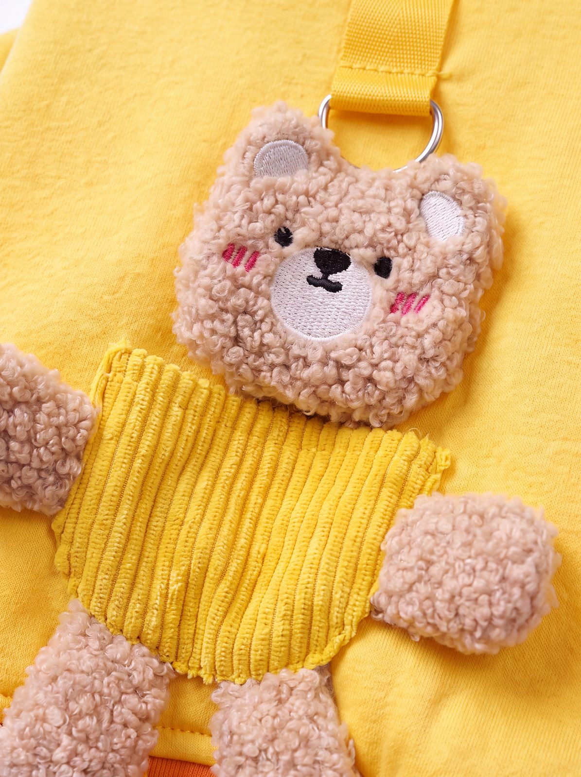 Gros plan sur l'ourson en peluche 3D du pull petit chien jaune