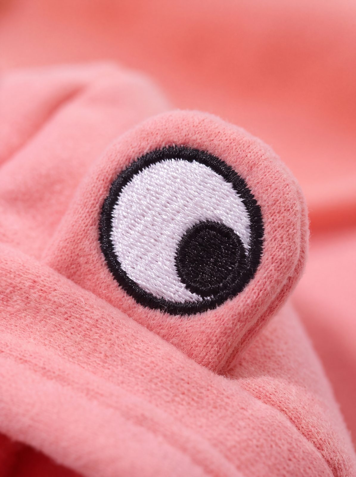 Macro d'un œil brodé de la capuche grenouille du sweat chien rose