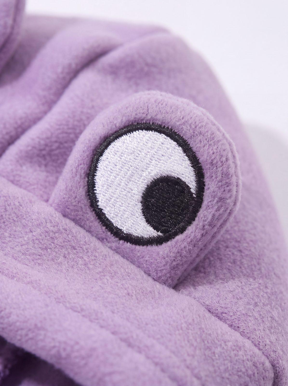 Gros plan sur l'œil brodé blanc de la capuche du sweat grenouille violet