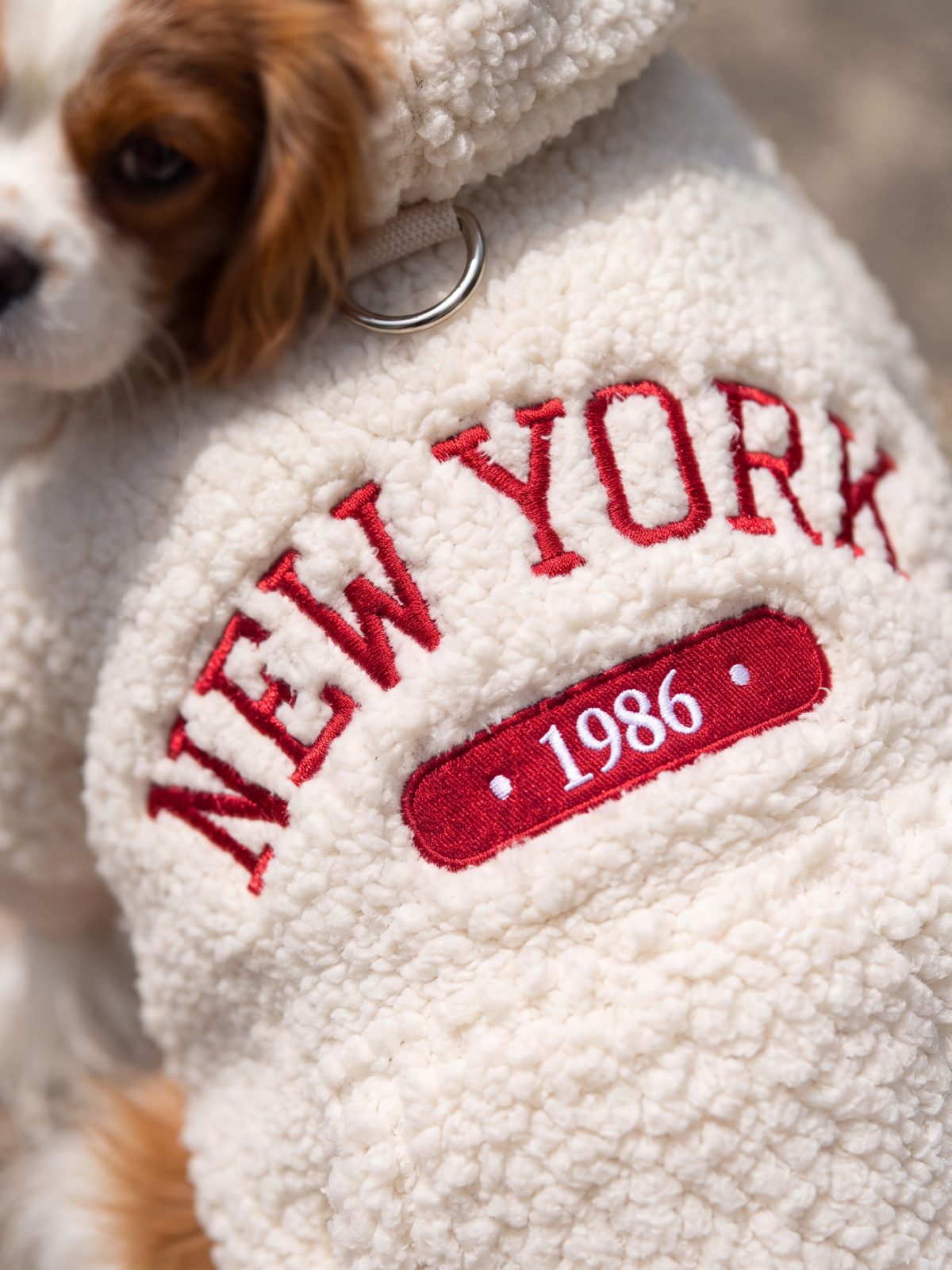 Gros plan sur la broderie rouge New York 1986 d'un sweat à capuche chien en sherpa crème