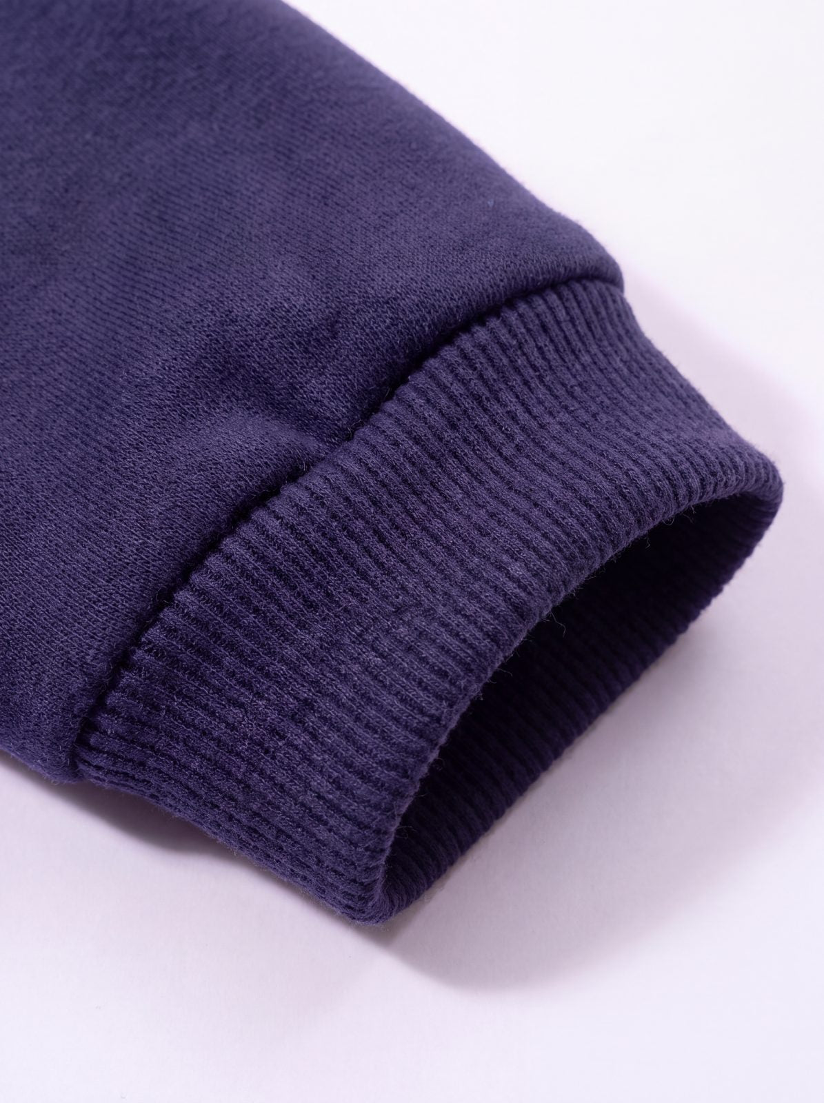 Gros plan sur le poignet côtelé du sweat à capuche chien bleu marine