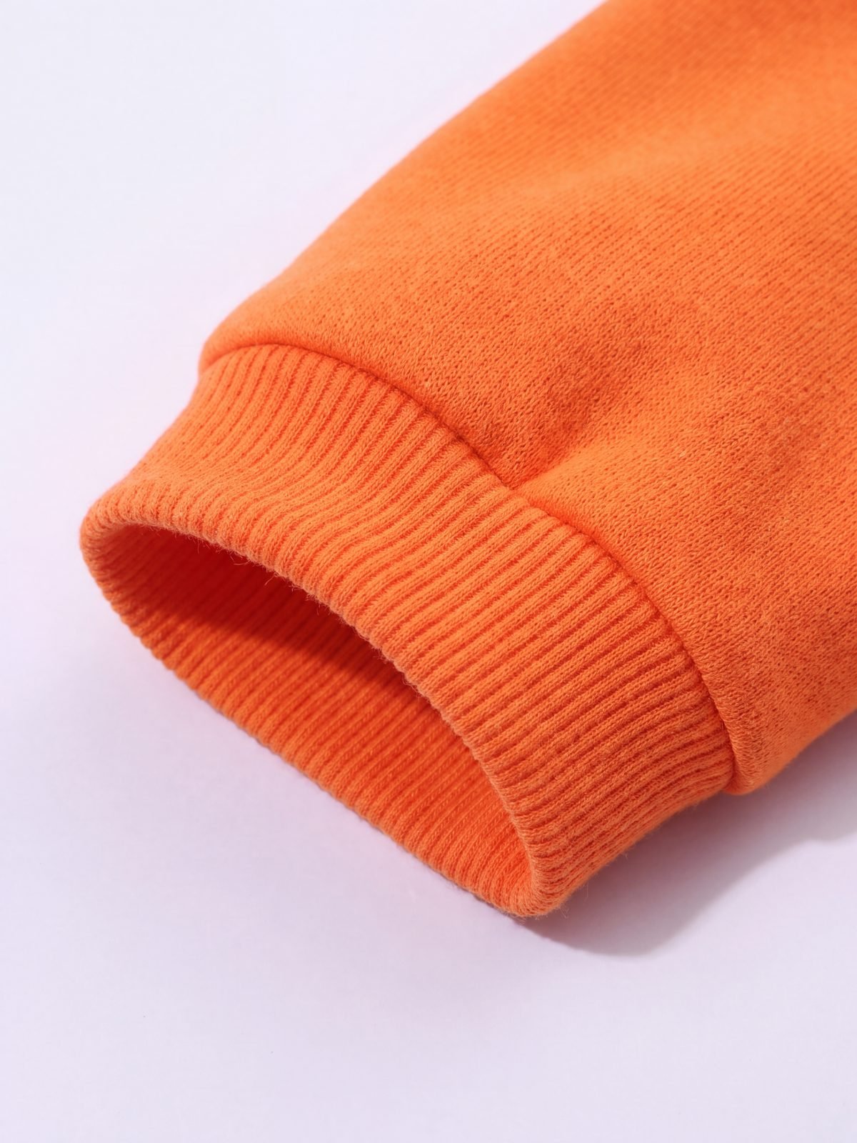 Gros plan sur le poignet côtelé du sweat à capuche chien orange