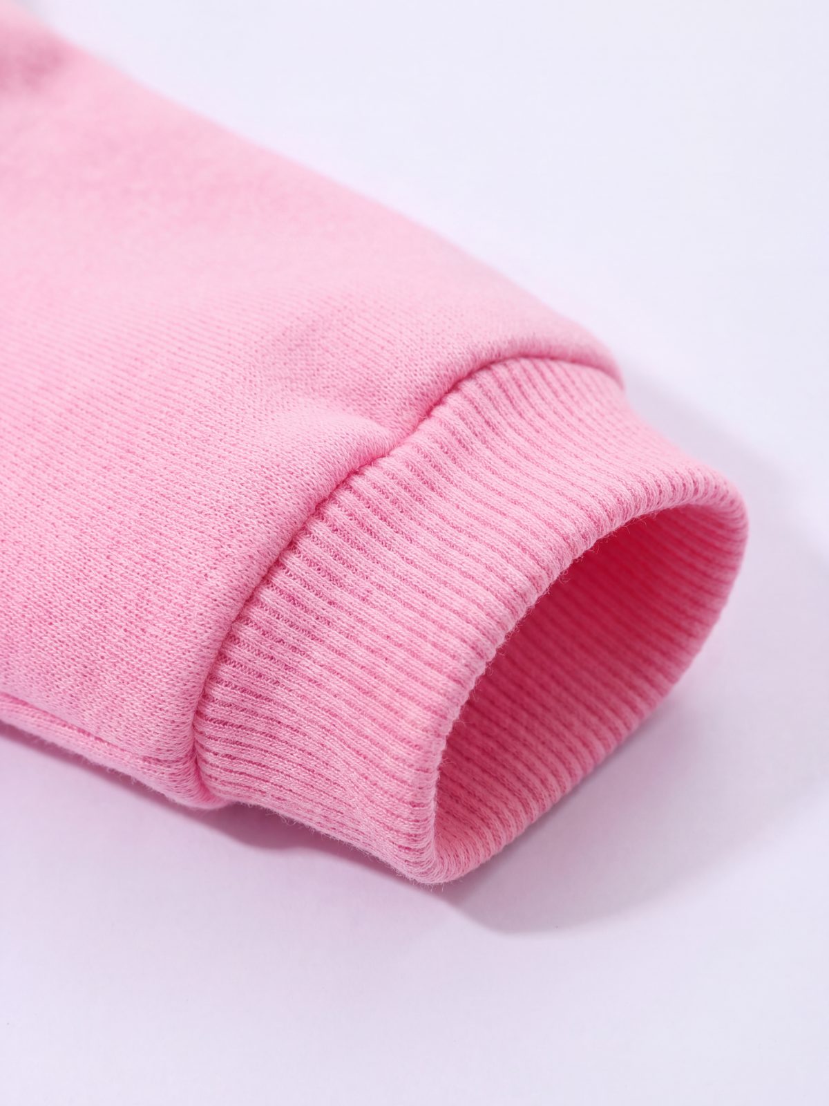 Gros plan sur le poignet côtelé du sweat à capuche chien rose